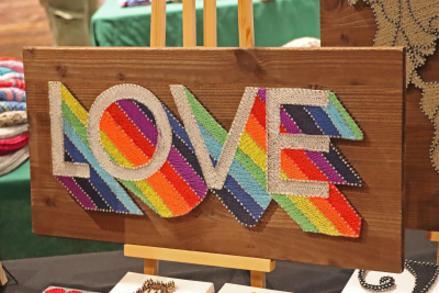 Regenbogenfarbiges Fadenbild mit Schriftzug "Love".