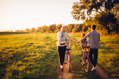 Familie spaziert mit Fahrrädern auf einem Feldweg