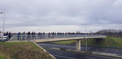 Eine Gruppe Menschen wandert gemeinsam über eine Straßenbrücke