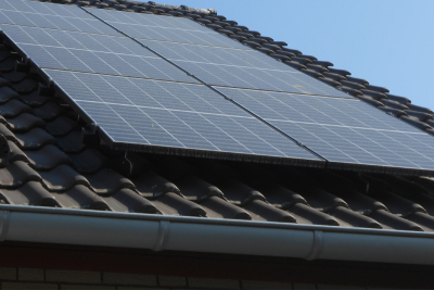 Eine Photovoltaikanlage auf einem Dach. Im Hintergrund blauer Himmel.