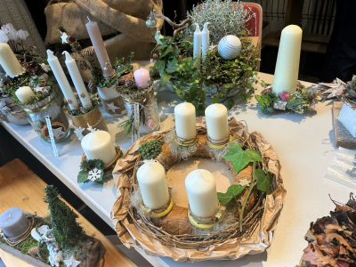 Dekorierte Kerzenständer und Gestecke mit Kerzen und Pflanzen sowie Adventskranz