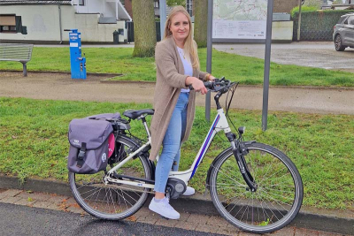 Niederkrüchtens Klimaschutzmanagerin Lea Korall mit einem eBike vor einer Übersichtskarte und Knotenpunkt-Hinweisschildern in der Gemeinde Niederkrüchten