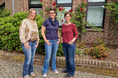 Peggy Löhr, Linda Königs und Marion Küpper vor der Rückseite des Rathauses in Elmpt. Im Hintergrund ein Rosenstrauch.